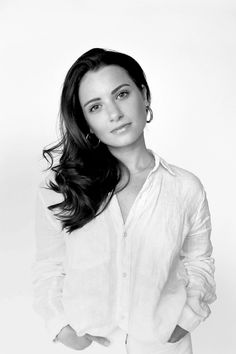 a black and white photo of a woman with her hands in her pockets, posing for the camera