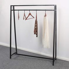 a coat rack with three coats hanging on it's sides and two hangers attached to the wall