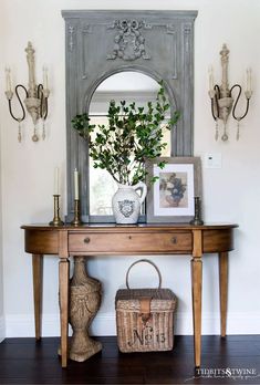 a wooden table sitting under a mirror next to a vase and potted plant on top of it