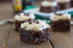 several brownies with white frosting and chocolate chips on top sitting on a wooden table