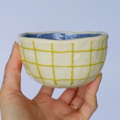 a hand holding a white and yellow bowl