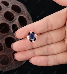 a woman's hand holding an engagement ring with a blue sapphire and white diamonds