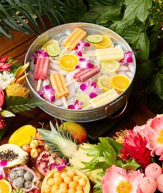 an ice bucket filled with popsicles, lemons, and other tropical fruit pieces