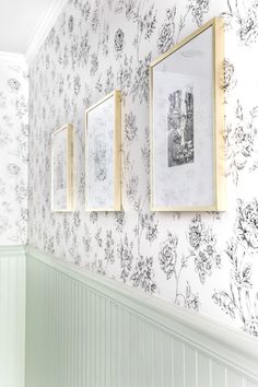 three framed pictures hang on the wall next to a white and green striped wallpaper