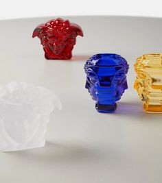 three different colored glass vases sitting on top of a white table next to each other