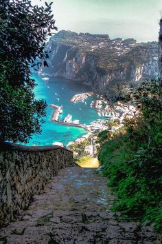 an old stone path leading to the beach and ocean in italy, with boats on the water