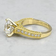 a yellow gold engagement ring with an oval cut diamond in the center and side stones