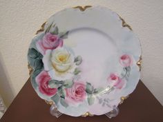 a plate with pink and white roses painted on it