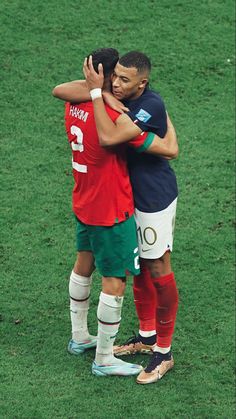 two soccer players hugging each other on the field