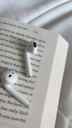 an open book with two earbuds laying on it's side next to each other