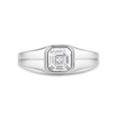 a white gold ring with an emerald cut diamond in the center, on a white background