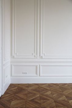 an empty room with wood flooring and white wall paneling on the walls is shown