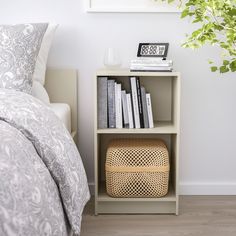 a bedroom with a bed, nightstand and bookshelf in the corner next to a potted plant