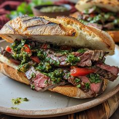 a roast beef sandwich with pesto and tomatoes on a white plate next to bread