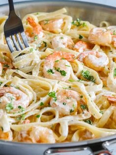 pasta with shrimp and parmesan cheese in a skillet being eaten by a fork