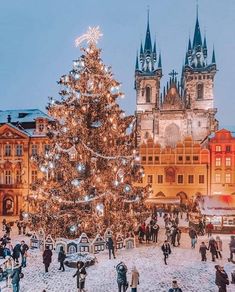 a large christmas tree in the middle of a town square with people walking around it