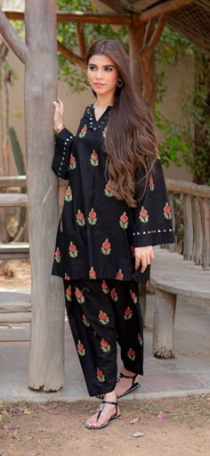 a woman standing next to a tree in front of a wooden structure with flowers on it