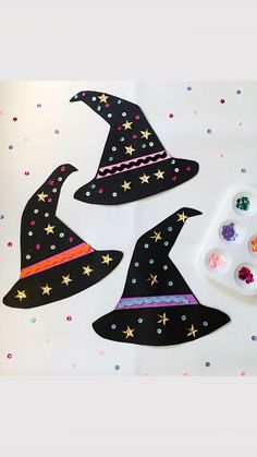 three witches hats with paint and glitters on the table next to them are crafting supplies