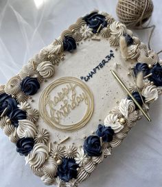 a birthday cake is decorated with blue flowers and gold letters that spell out happy birthday