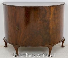 an antique wooden cabinet with glass top and metal handles on the bottom, in front of a white wall