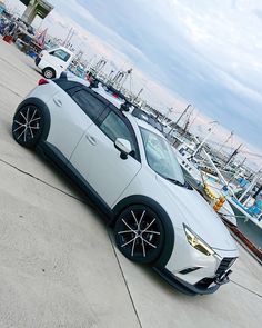 a white sports car parked in front of some boats