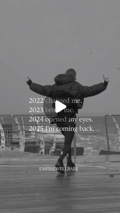 a person standing on top of a pier next to the ocean with their arms outstretched