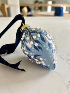 a blue and white ornament sitting on top of a table next to a black ribbon