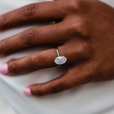 a woman's hand with a diamond ring on top of her left hand,