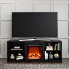 an entertainment center with a fire place and television on top, in front of a white wall