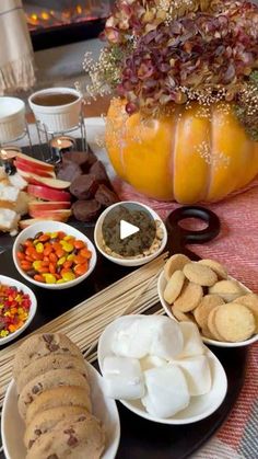 a table topped with lots of food next to a vase filled with flowers and pumpkins