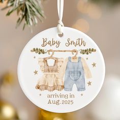 a baby's first christmas ornament with two clothes hanging from a tree