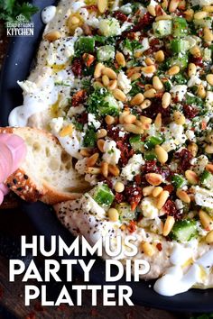 hummus party dip platter with pita bread on the side and garnished with nuts