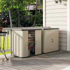 an outdoor storage shed with its doors open on a deck next to a table and chairs