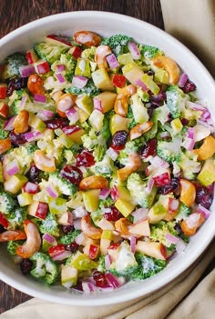 a white bowl filled with broccoli, cranberries and other food items