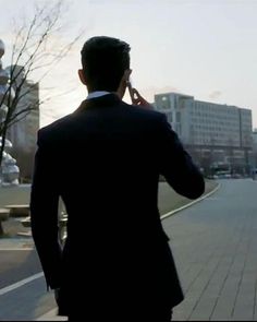 a man in a suit is talking on his cell phone while walking down the street