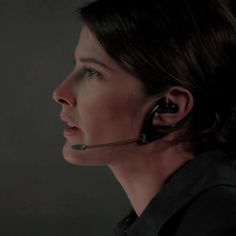 a woman with earplugs on her ears looking off to the side in a dark room