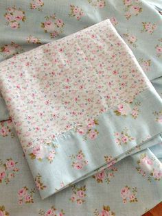 three pieces of blue fabric with pink flowers on them and one piece is folded up