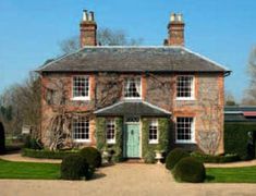 a large brick house with hedges around it