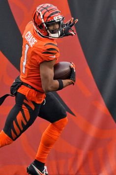 a football player running with the ball in his hand and wearing an orange jersey that says tiger on it