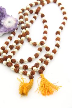 These beautiful beads are made from Rudraksha seeds paired with pearls. Hailing from India, Rudraksha seeds are traditionally used as prayer beads in Hinduism. They are the seeds of the Rudraksha tree, and legend has it that when Lord Shiva awoke from a long meditation, he shed a tear; from this tear grew the Rudraksha tree.Pearls are known as "moti" in Hindi, and they are symbolic of the moon. They encourage positive thinking and balance, and are believed to attract good luck and wealth. Bead S Spiritual Beaded Necklace With Spacer Beads For Festivals, Spiritual Beaded Necklaces With Spacer Beads For Festivals, Spiritual Polished Beads For Puja, Polished Pearl Necklace For Festivals, Festive Pearl Necklace With Polished Beads, Festival Pearl Necklace With Polished Beads, Festival Polished Pearl Necklace, Spiritual Gemstone Beads Mala For Puja, Spiritual Gemstone Mala For Puja