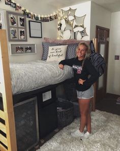 a woman is standing in front of her bed