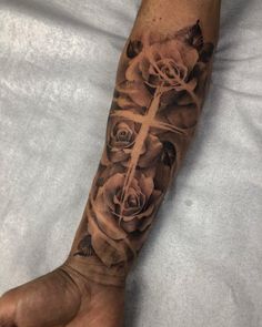 a person with a cross and roses tattoo on their arm