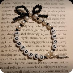 a beaded bracelet with words written in white and black beads on top of an open book