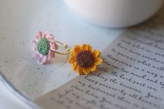 two crocheted flowers sitting on top of an open book