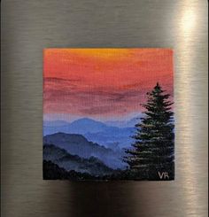 an acrylic painting of mountains and trees on a metal surface with the sun setting