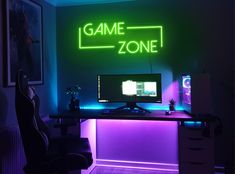 a gaming room with neon lights and a computer on a desk in front of the game zone sign