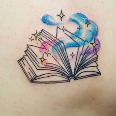 an open book tattoo on the back of a woman's upper arm with stars and clouds coming out of it