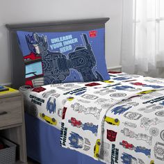 a bed with a blue and white bedspread on top of it next to a night stand