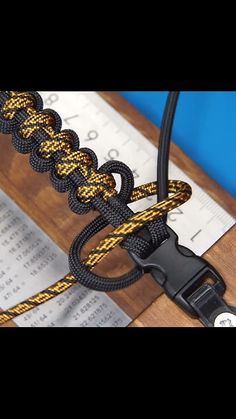 a close up of a black and yellow rope on a wooden surface with a ruler in the background