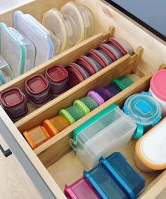 a drawer filled with lots of different colored containers and lids on top of each other